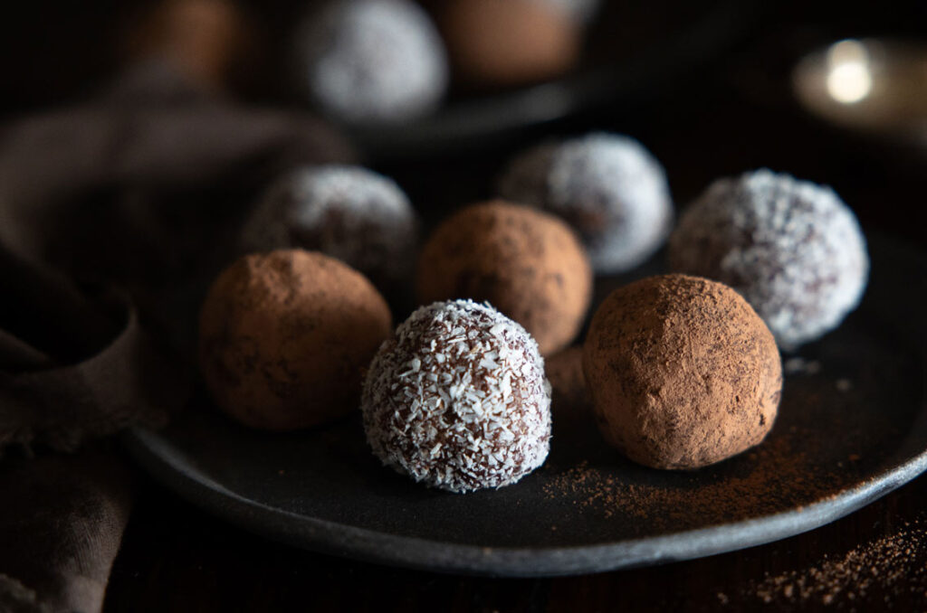 Image of chocolate truffles on a plate. Half are dusted with cocoa, the other half with coconut.