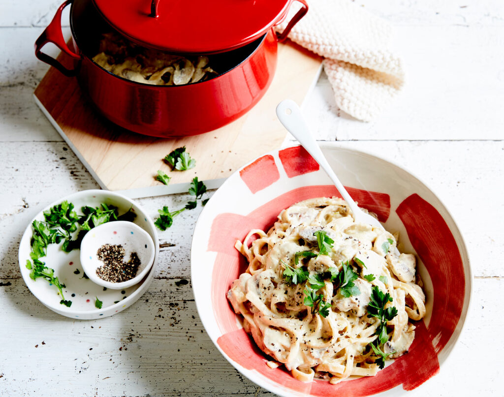 A bowl of creamy pasta alfredo is ready to serve, garnished with parsley.