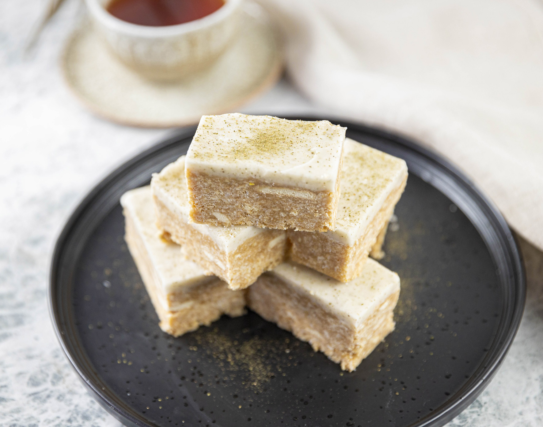 mouth watering vegan lemon slice on plate with a cup of tea on side