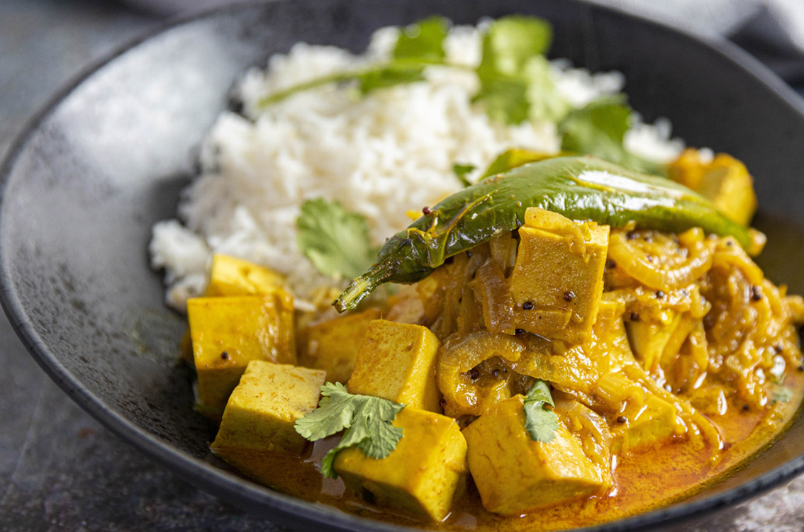 Close up of delicious looking tofu masala curry with rice on side in a bowl