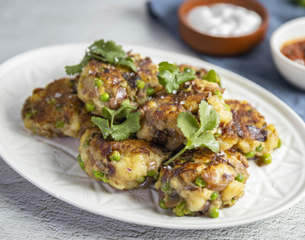 spiced potatoes patties on plate with herbs on top and dips on side