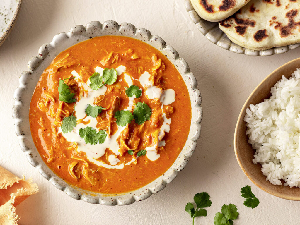 Overhead image of a creamy plant-based butter 'chicken' with a side of rice and naan.