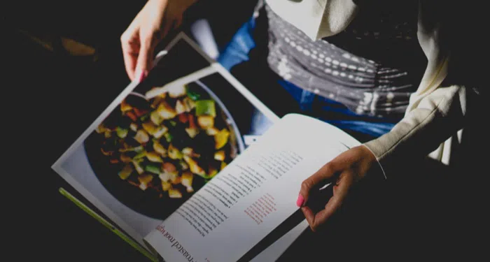 Overhead image of person flicking through a recipe book.