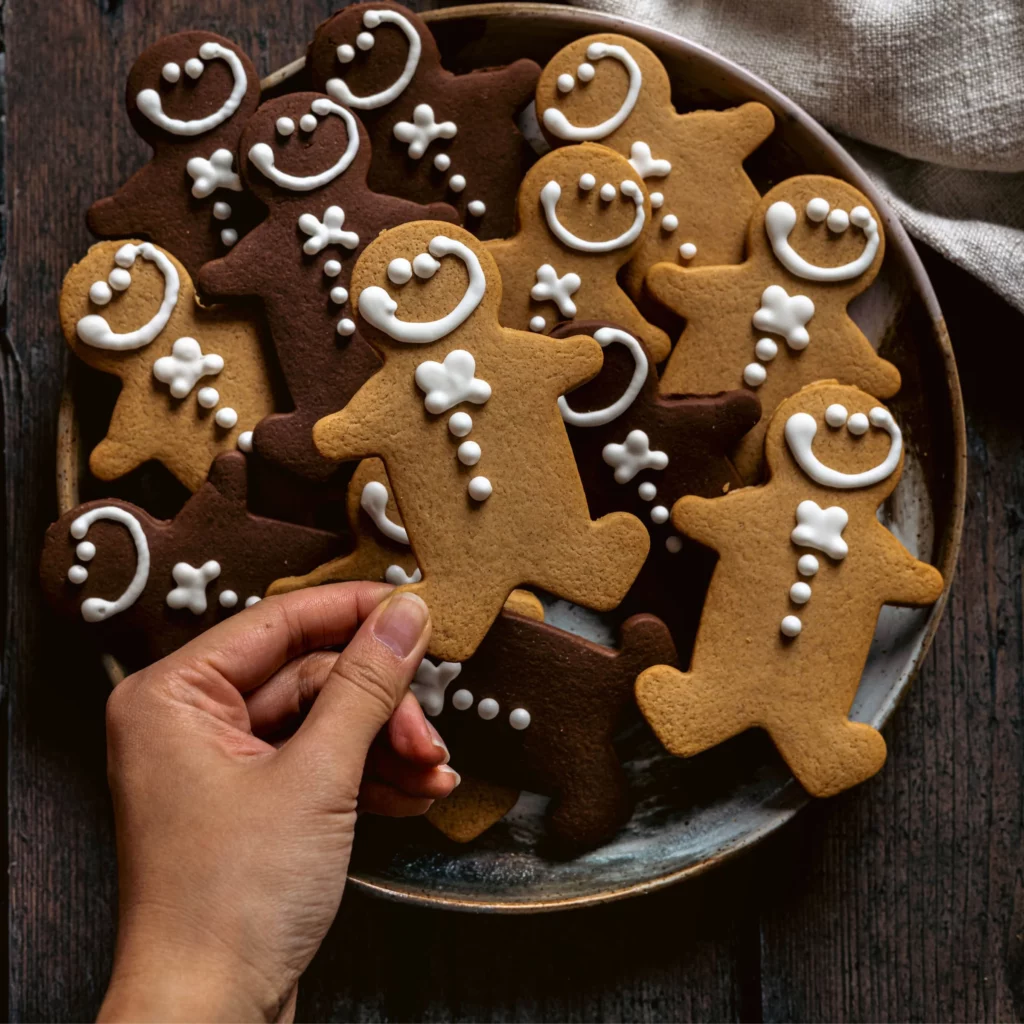 An image taken overhead of a plate of traditional and chocolate gingerbread, with a hand lifting one to camera.