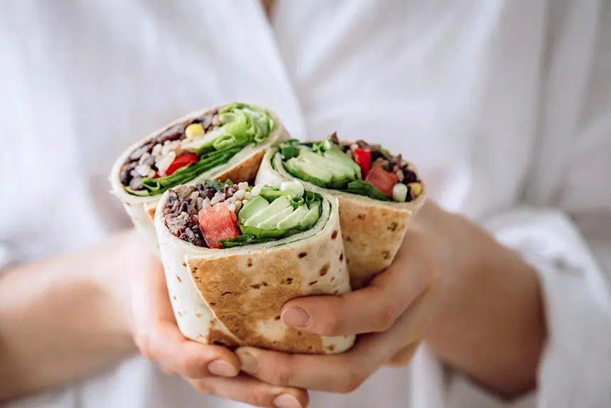Close up image of hands holding salad wraps.