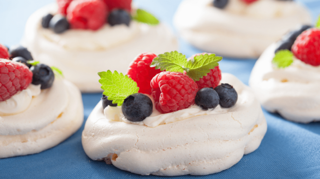 A front on image of mini pavlovas topped with berries.