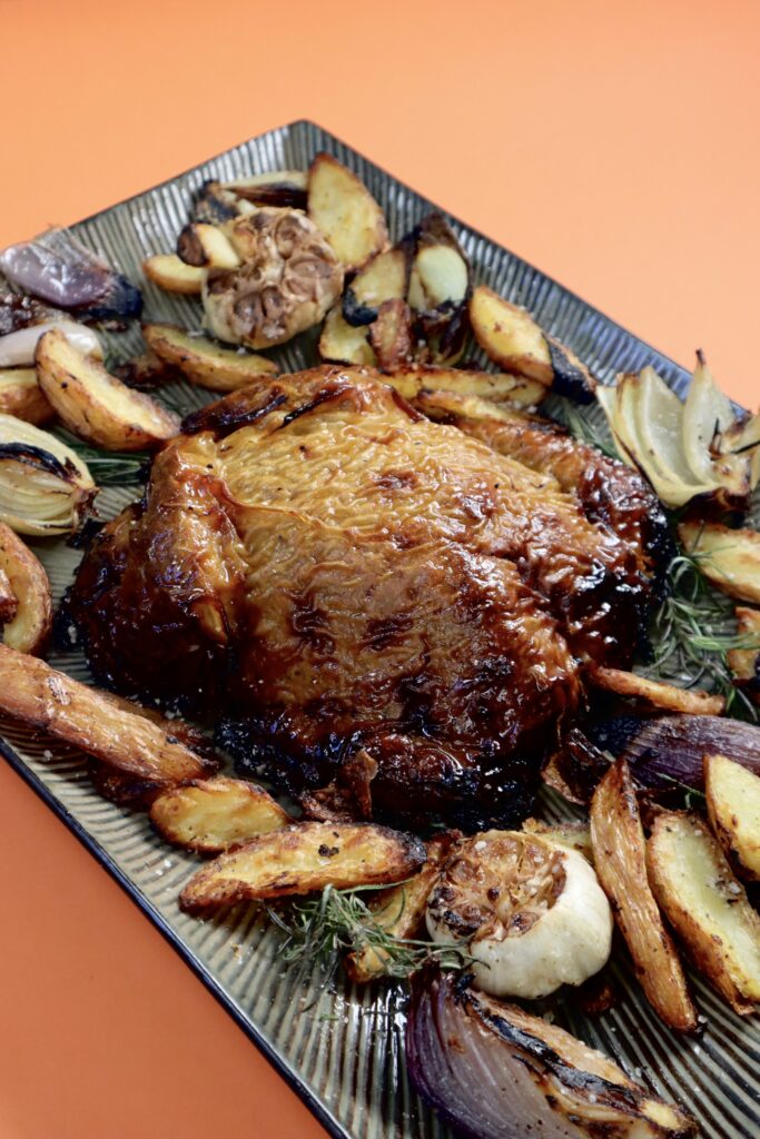 An overhead image of a whole vegan turkey on a platter surrounded by roast veg.