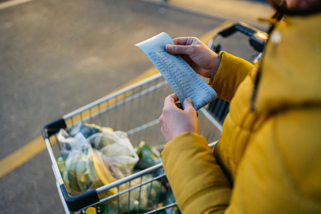 Close up of hands holding receipt from the grocery store at night.