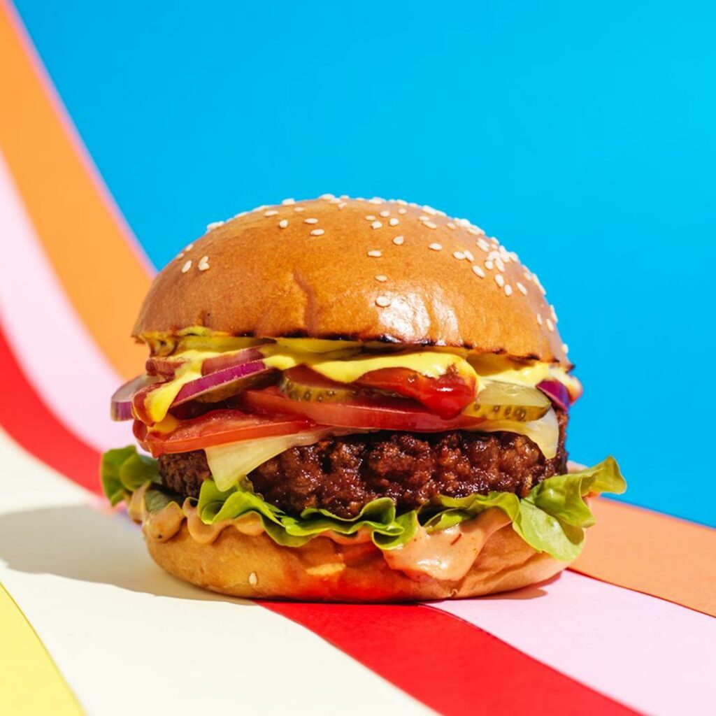 Front-facing shot of a delicious looking plant-based burger on a colourful background.