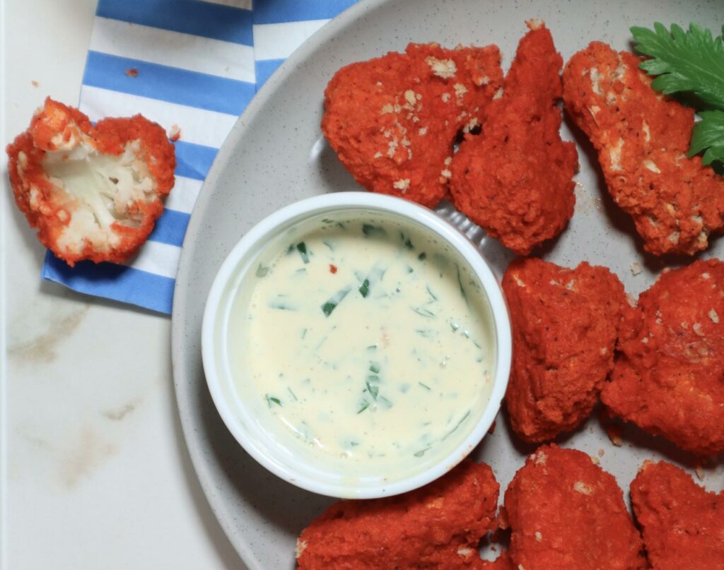 Overhead image of deep-fried buffalo cauliflower bites with a side of ranch.