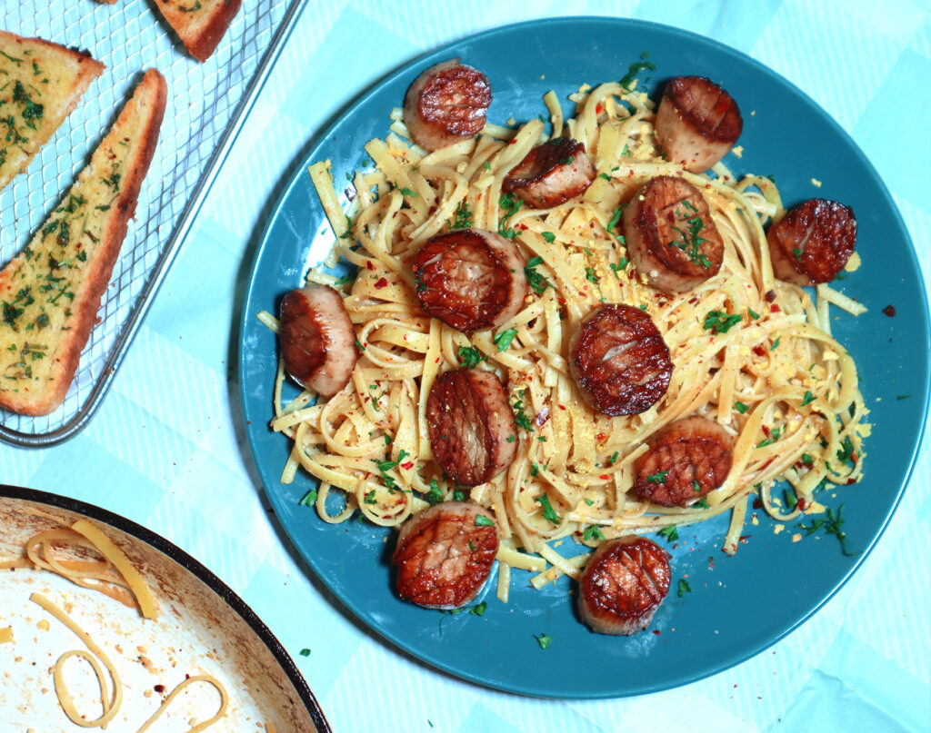 An overhead image of a pasta dish topped with king oyster mushroom scallops. 