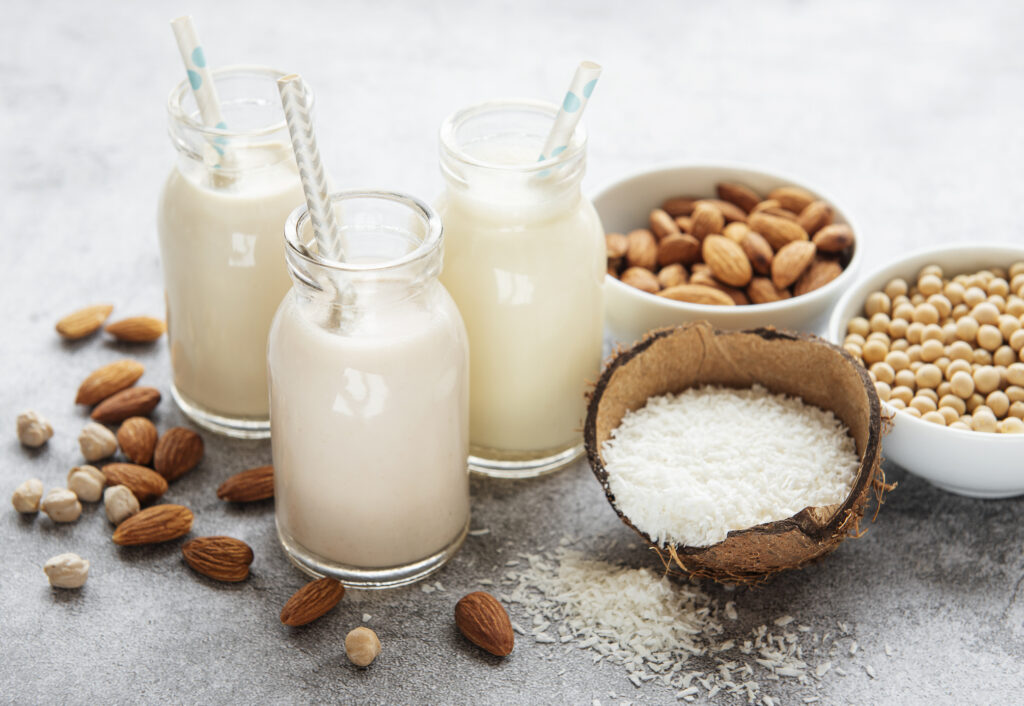 Alternative types of vegan milks in glass bottles on a concrete background. Top view