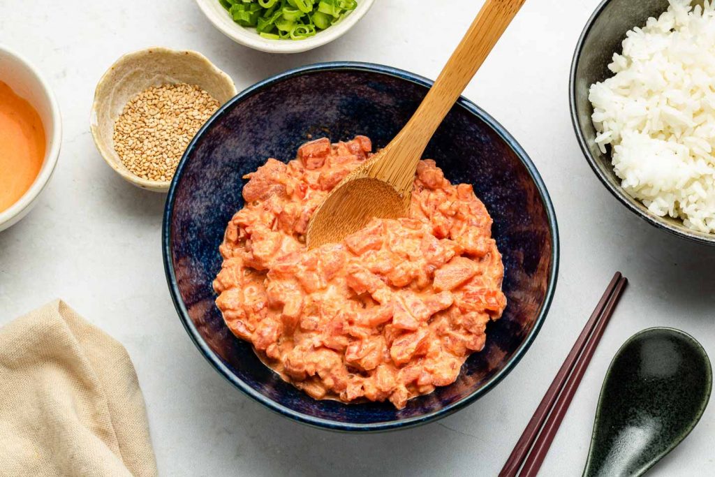 Overhead shot of a bowl on a bench filled with a creamy orange/red looking 'tuna' mix.