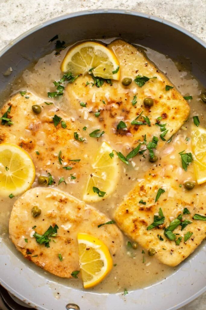 Overhead image of a bowl of vegan 'chicken' piccata: pan-seared tofu fillets in a creamy lemon and caper sauce.