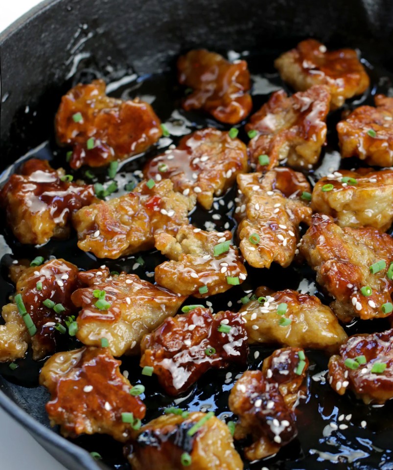 Close-up image of vegan 'chicken' bites in a pan soaked in a rich marinade.