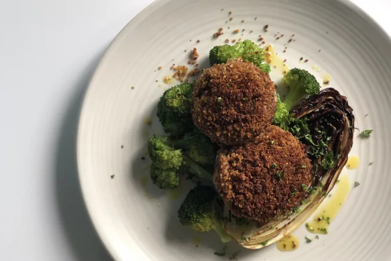 Two crispy Kievs sit atop a bed of broccoli and charred lettuce.