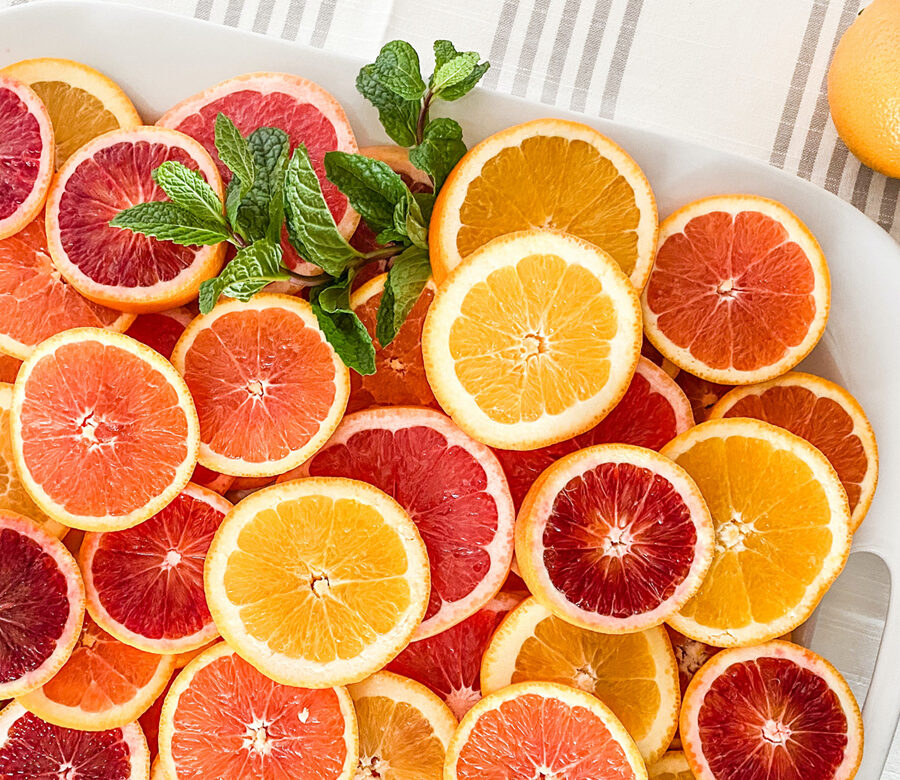 A red, orange, and yellow palette of sliced citrus fruits on a tray.