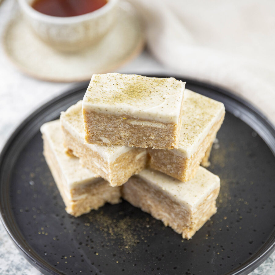 mouth watering vegan lemon slice on plate with a cup of tea on side