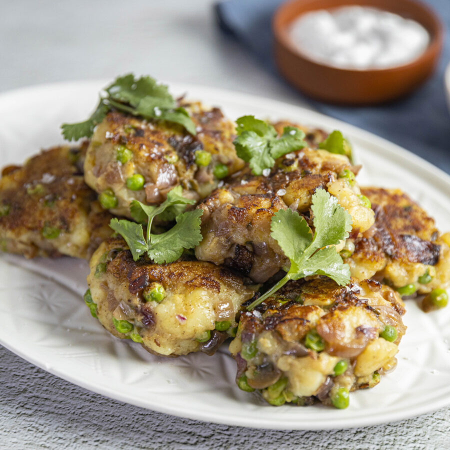 spiced potatoes patties on plate with herbs on top and dips on side