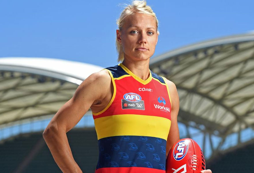 Erin Phillips wearing her Adelaide guernsey holds a football.