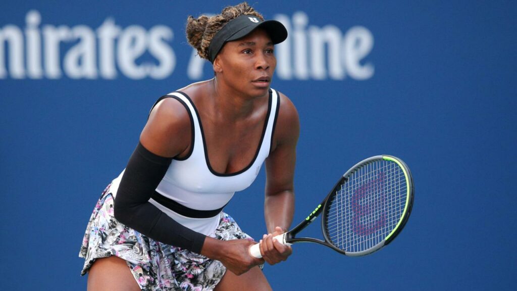 Venus Williams preparing to return serve on the tennis court. 